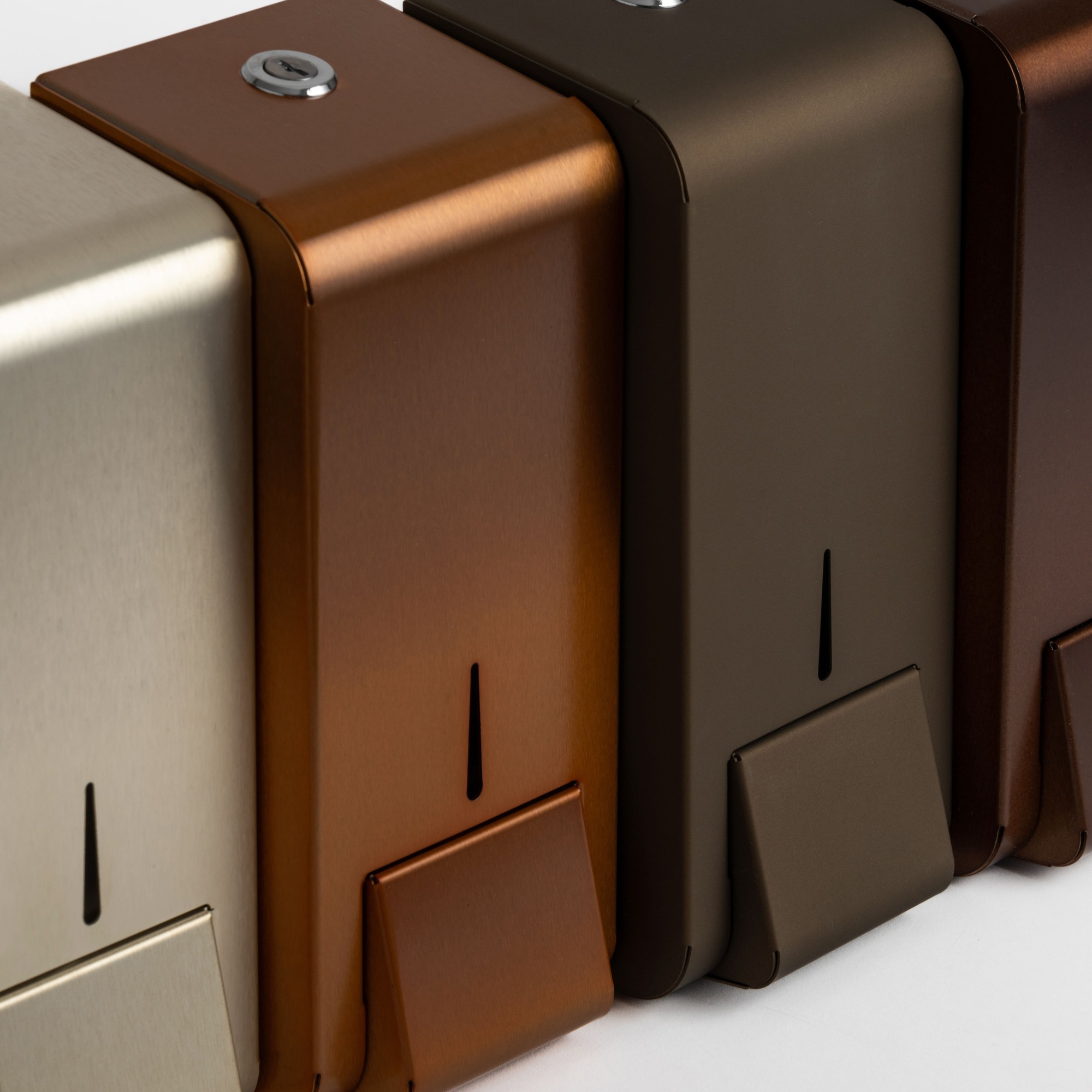 Opal sæbedispenserne i stål ved siden af hinanden i forskellige belægninger herunder kobber belægning, keramisk belægning og PVD champagne belægning